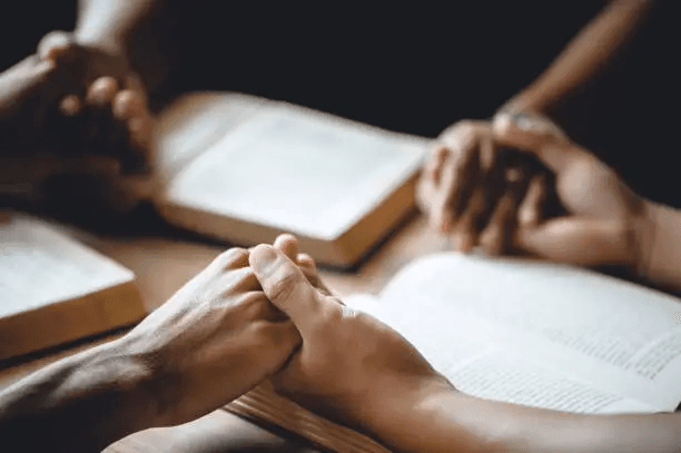 Hands in prayer over Bible